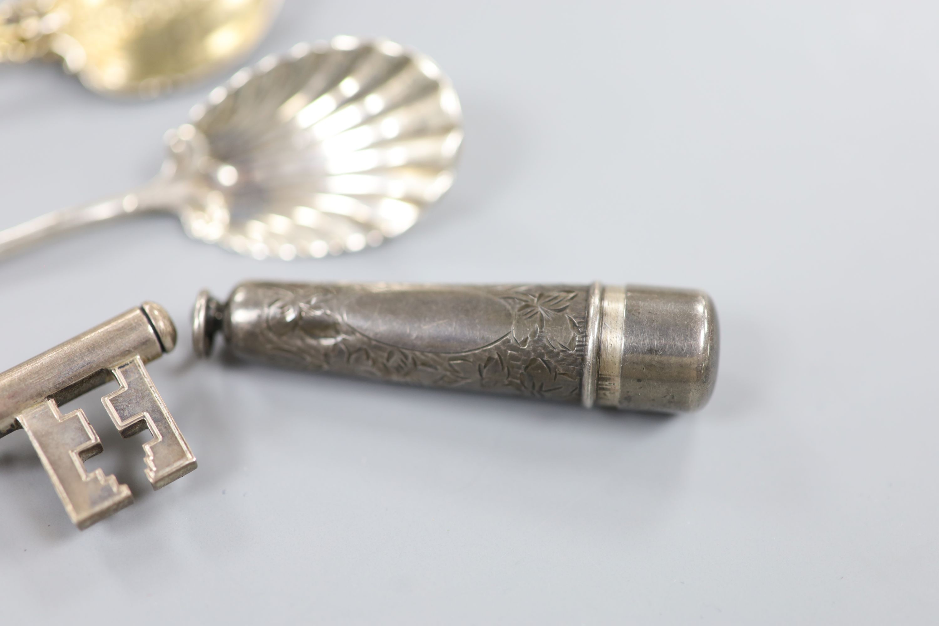 A 1939's silver presentation key, London, 1935, 10.2cm, a white metal cheroot holder case and a similar silver case, an engraved white metal cased propelling pencil and four silver long hollow spoons, with pierced bowls.